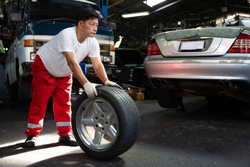 Fototapeta na wymiar mechanic holding and pushing a tire for fixing in garage