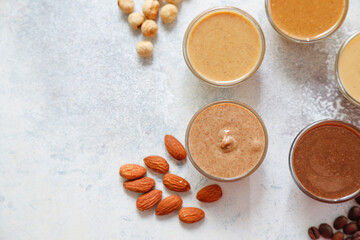 Homemade nuts butter in a glass jars with various nuts.