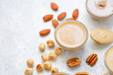 Homemade nuts butter in a glass jars with various nuts.