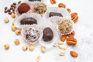 Superfood, raw healthy vegetarian snack, Medjool dates covered by chocolate, and various energy balls with nuts.