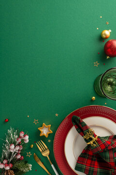 Design festive table setting: Top-view vertical image of plate, golden flatware, checkered napkin with ring, glass, balls, natural Christmas tree twigs, candle, glimmering confetti, mistletoe on green