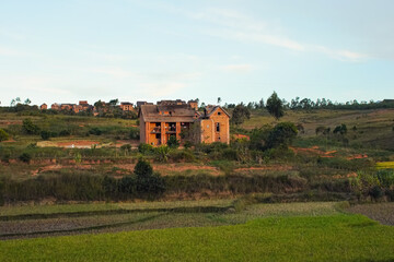 Fototapeta na wymiar Typical Madagascar landscape - green and yellow rice terrace fields on small hills with clay houses in region near Fianarantsoa