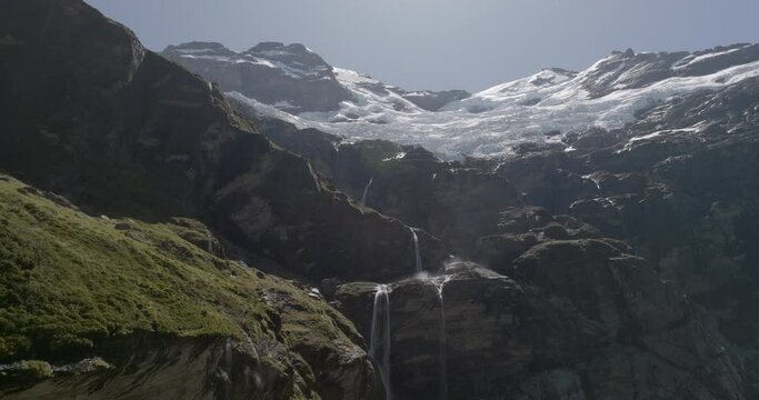 Aerial Backward Shot Of Waterfall And Mountains On Sunny Day, Drone Flying Over Landscape - Otago, New Zealand
