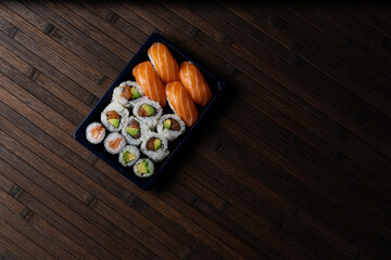 Sushi to Go. Dark Mood Shot of Sushi Tray on Wood Background. copy space