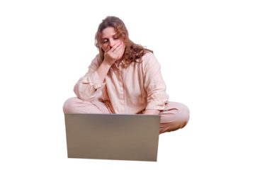 A woman yawns while sitting at her laptop in the evening room, isolated on a white background. Red-haired woman working with food on the bed.