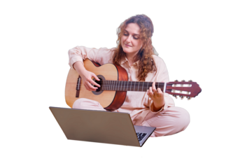 Young woman plays the guitar while sitting on the bed with a cat, online music lessons, isolated on a white background. Woman with a musical instrument in her hands in the home bedroom with laptop