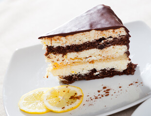 Slice of delicious chocolate lemon cake served on white plate with sliced lemon ..