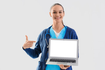 Female medical intern pointing at laptop on white background