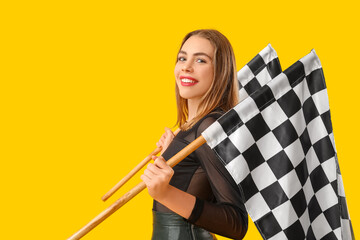 Beautiful young woman with racing flags on yellow background