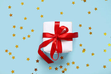 Christmas gift box and confetti on blue background