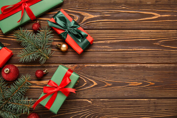 Gift boxes with Christmas tree branches and balls on wooden background