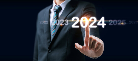 Goal. businessman hand touching and pointing on year 2024 with virtual screen on dark background,...