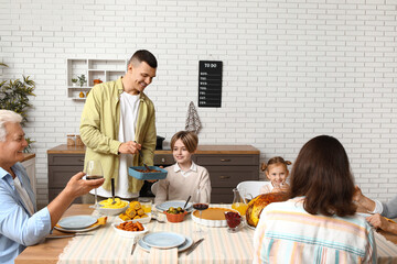 Happy family having dinner at festive table on Thanksgiving Day