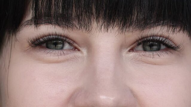 A close up portrait of young beautiful woman with green eyes, smiling looking at camera. beautiful brunette girl with short bang is opening and blinking her eyes. natural beauty.