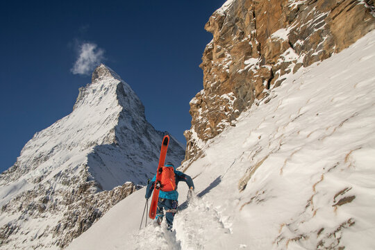 Person with ski equipment climbing snowcapped mountain