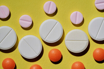 Medicine and drug concept. Pharmacy and health care. Close up of different tablets pattern on yellow background.