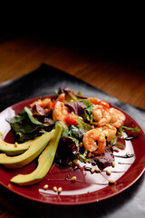 Salad with avokado and shrimps on a wooden table. Healthy food.