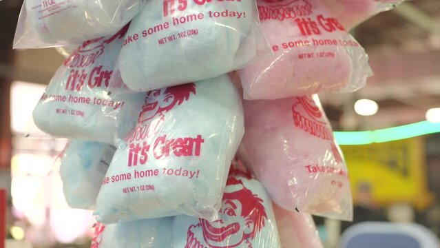 This video shows a display of classic pink and blue bags of cotton candy with a busy background.