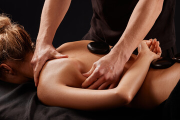 Fototapeta premium A man receives a hot stone massage, a masseur gives a stone massage