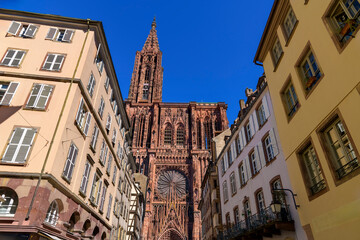 The tower and spire of the Strasbourg Cathedral or Cathédrale Notre-Dame-de-Strasbourg, Our Lady of Strasbourg, rise above the medieval streets in the old town of Strasbourg, France.