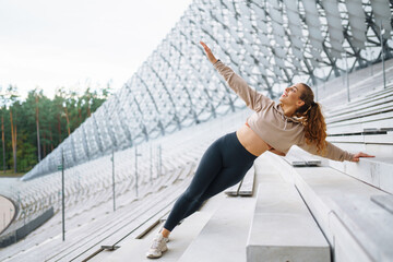 Athletic woman performs sports exercises outdoors. A young female athlete in special clothing is...