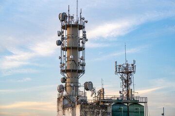 Two towers with communications antennas on top of a building. In the background, the blue sky with some clouds.