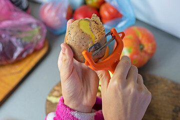 hands of a girl peeling potatoes in the kitchen before cooking