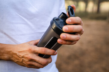 athlete man caucasian male hold supplement shaker outdoor in nature
