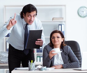Old female boss and young male employee in the office