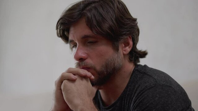 One preoccupied young man thinking deeply about life problematic issues. Worried male person in 30s with hand in chin with thoughtful expression