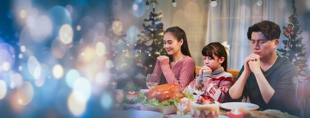Asian happy family celebration on christmas day, sitting and closed eyes keep hands folding in...