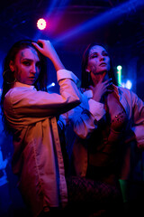 Two Beautiful go-go dancers in makeup in lingerie and white shirts pose in a nightclub. Party...