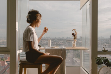 Relax asian woman eating at balcony window good warm vibes weekends lifestyle.