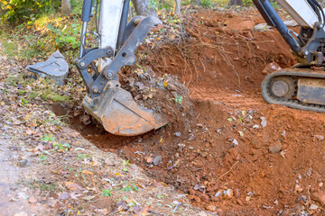 Worker use tractor digs out ditch for laying drainage concrete sewage pipe