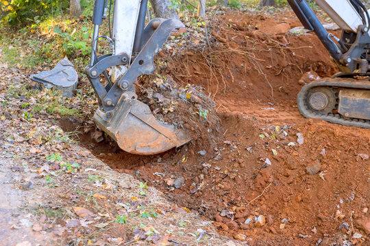 Worker use tractor digs out ditch for laying drainage concrete sewage pipe