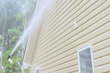 Using high pressure nozzles, service worker efficiently washes siding houses with water soap cleaner