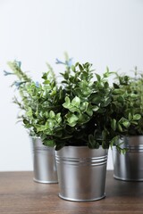 Different artificial potted herbs on wooden table against white background, closeup