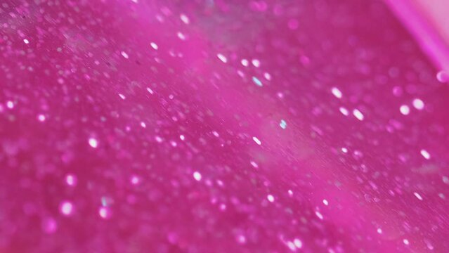 Shimmering background. Glitter sand. Bright pink shimmer fluid paint wave with bokeh light spreading in trendy abstract captivating hypnotic art.