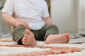 Baby sitting on soft carpet indoors, closeup