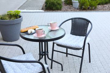 Cups of coffee, bread and cheese on glass table. Relaxing place at outdoor terrace