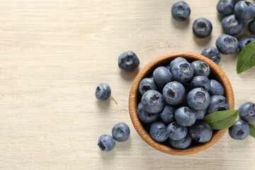 Bowl of fresh tasty blueberries on white wooden table, flat lay. Space for text
