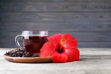 Delicious hibiscus tea and flowers on wooden table. Space for text