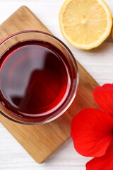 Delicious hibiscus tea, lemon and beautiful flower on white wooden table, flat lay