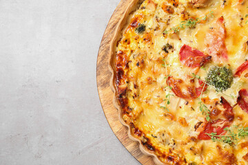 Tasty quiche with cheese and tomatoes on light grey table, top view. Space for text
