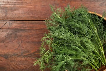 Bowl of fresh green dill on wooden table, top view. Space for text