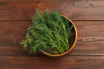 Bowl of fresh green dill on wooden table, top view