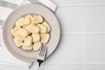 Plate of tasty lazy dumplings and fork on white tiled table, flat lay. Space for text