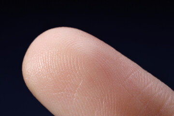 Finger with friction ridges on dark background, macro view