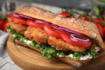 Delicious sandwich with schnitzel on wooden board, closeup