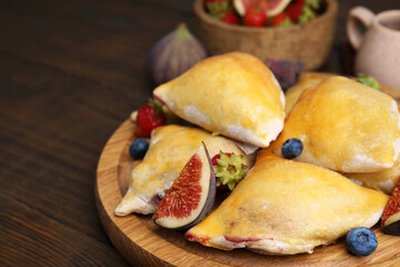 Delicious samosas with figs and berries on wooden table, closeup. Space for text